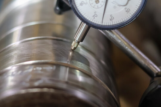 Dial indicator measuring car transmission shaft runout.