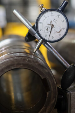Dial indicator measuring car transmission shaft runout.