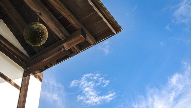 軒裏の梁と杉玉を見上げた酒蔵 秋の青空と木組み 初秋の和の建築