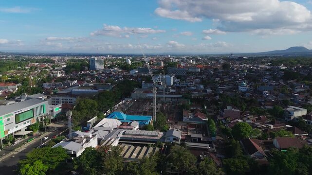 Malang, East Java, Indonesia - 23 July 2026: Aerial view of hotel building construction with a crane in the city center.