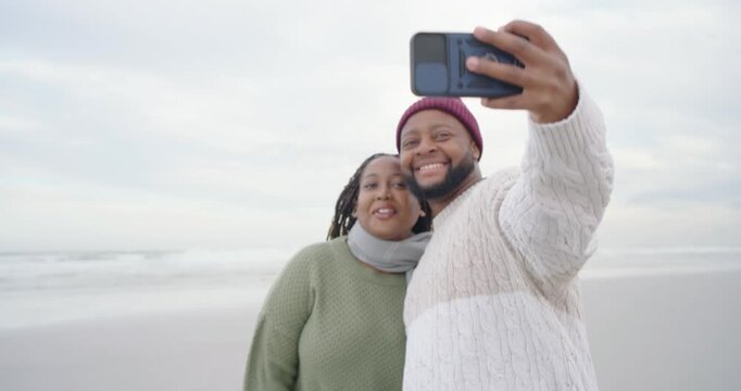 Couple walking on sandy shore man reaching pocket with smartphone taking selfies saving memories