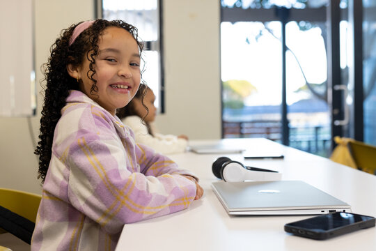 African American preteen girls sitting at school wearing headband, laptop headphones, copy space