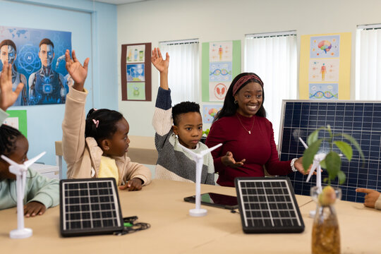 African American teacher leading children in STEM activity in classroom using solar panels, tablet