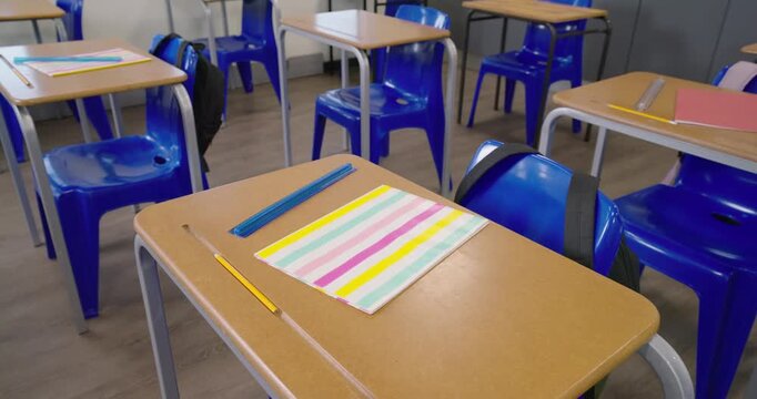 Camera starting to drift right, bringing classroom desk with notebook, pencil and ruler into focus