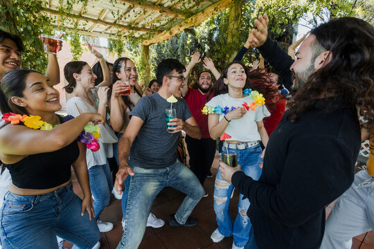 large group of latin friends dancing in a party in terrace outdoors in Mexico Latin America. Diverse Hispanic people men and women multi age having fun