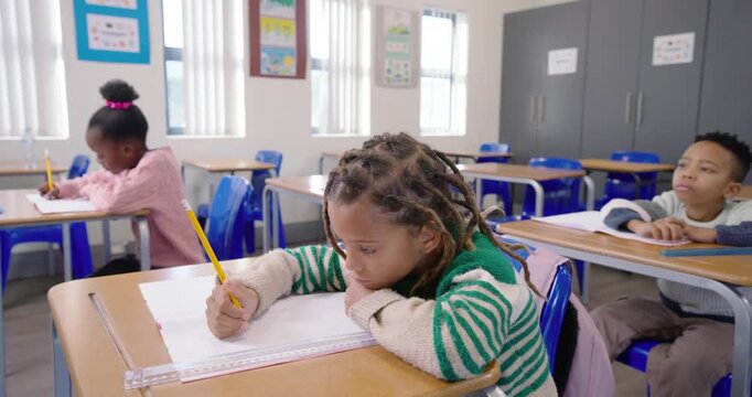 African American students writing in class, center student pausing with yellow pencil and notebook