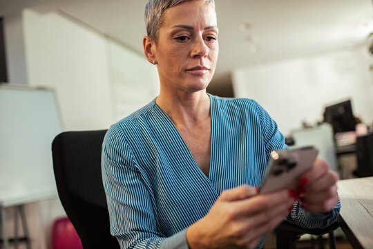 Focused businesswoman using smartphone in modern office