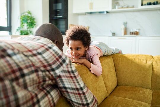 Parent and daughter playing on sofa at home