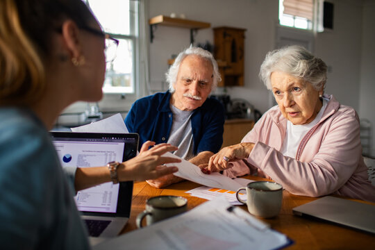Senior couple meeting financial advisor at home kitchen table