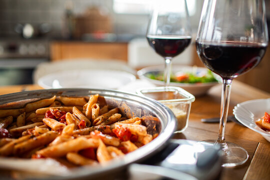 Homemade penne pasta dinner with red wine on home kitchen table