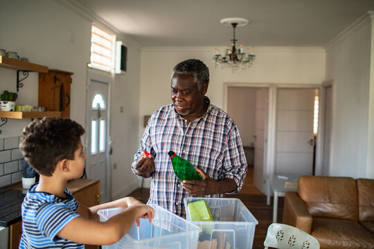 Senior man teaching boy recycling in home kitchen