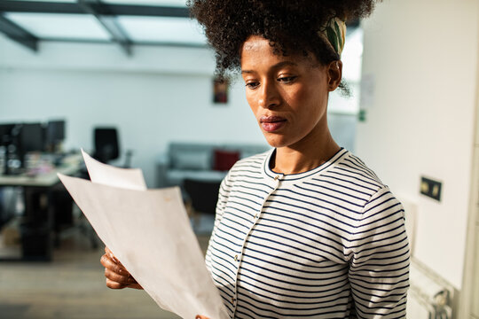Focused woman reading paperwork in modern office