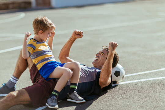 Father and son celebrating soccer goal on outdoor court