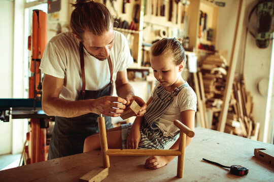 Parent teaching child woodworking in home workshop