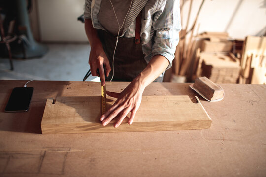 Carpenter measuring wooden board in workshop