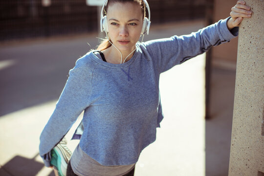 Female runner stretching with headphones outdoors