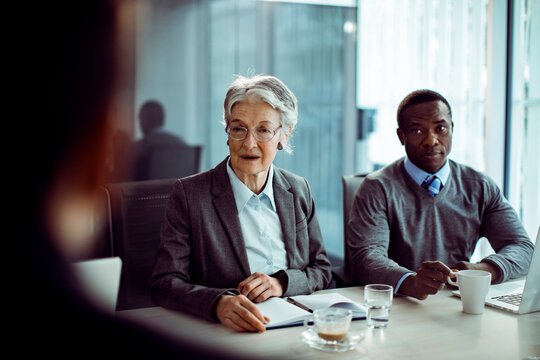 Senior businesswoman and colleague interviewing candidate in modern office