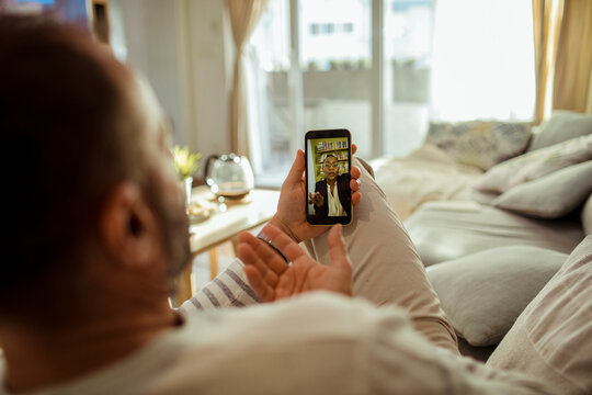 Man on sofa video calling a therapist at home
