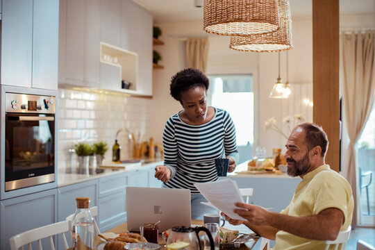 Couple reviewing household bills in home kitchen