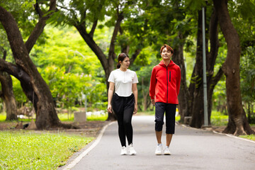 Obraz premium Happy active Asian couple having fun walking holding hands in park outdoors. romantic seasonal concept