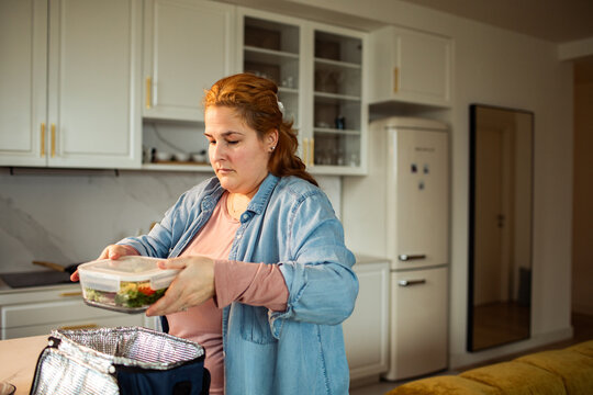 Woman packing lunch into insulated bag in home kitchen