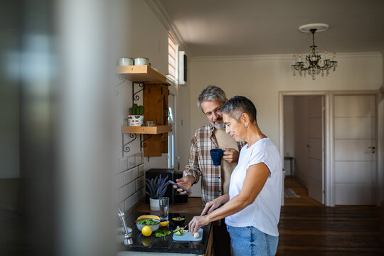 Mature couple preparing healthy meal together in home kitchen