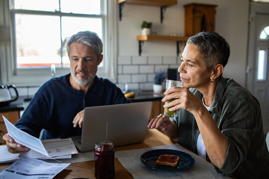 Middle-aged couple paying bills at kitchen table