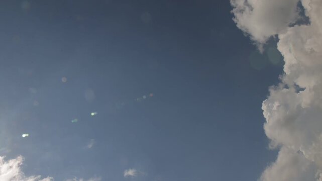Time-lapse of bright cumulus clouds growing darker and covering the sun in a changing daytime sky