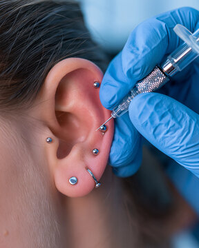 Professional Ear Piercing Procedure in Tattoo Shop with Sterile Equipment - Enhancing Beauty with Metal Jewelry and Gemstones