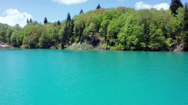Forest-framed Green Lake fills aerial view with clear turquoise water and wooded slopes near Goderdzi Pass, supporting ecotourism, regional travel, conservation media, Georgian destination promotion