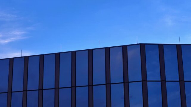 Charlotte, North Carolina - 22 July 2026: Aerial view of modern glass building facade reflecting the blue sky.
