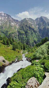 Stunning mountain scenery in the Alps with waterfall, peaks and meadows in summer