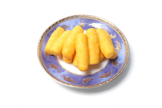 top-down view of crunchy yellow cheese corn puffs piled on a small blue and white patterned ceramic saucer.
