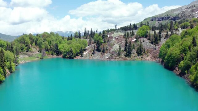 Turquoise Green Lake opens beneath descending aerial view beside mixed woodland and highland slopes near Goderdzi Pass, supporting ecotourism, freshwater geography and Georgian travel campaigns.