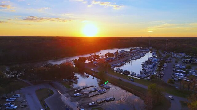 Lake County, Florida, United States - 21 July 2026: Aerial view of Crows Bluff marina during golden hour with boats docked along the river and surrounding trees.