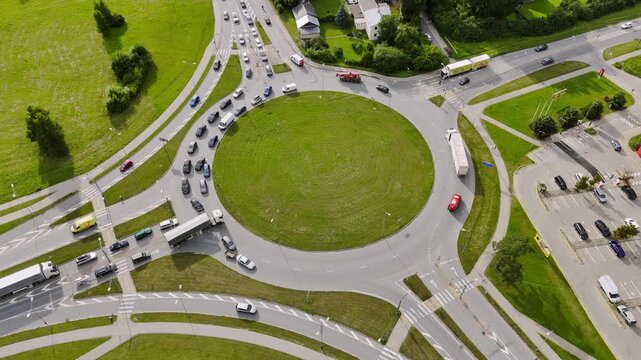 Riga, Latvia - 21 July 2026: Aerial view of a busy roundabout with cars and trucks circulating around a green central island.