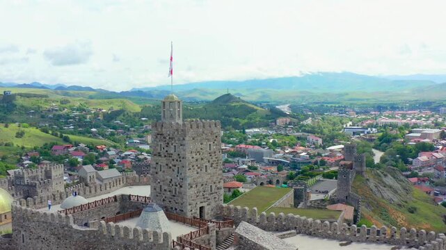 Aerial drone retreats from Rabati Fortress in Akhaltsikhe, Georgia, revealing towers, mosque dome, fortified walls and city panorama for cultural heritage, religious architecture and tourism promotion