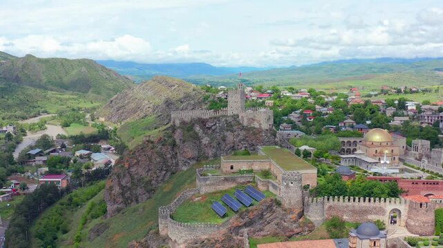 Aerial drone tracks Rabati Fortress sideways in Akhaltsikhe, Georgia, revealing the hilltop complex, surrounding town and mountain landscape for historical tourism, geography and travel marketing.