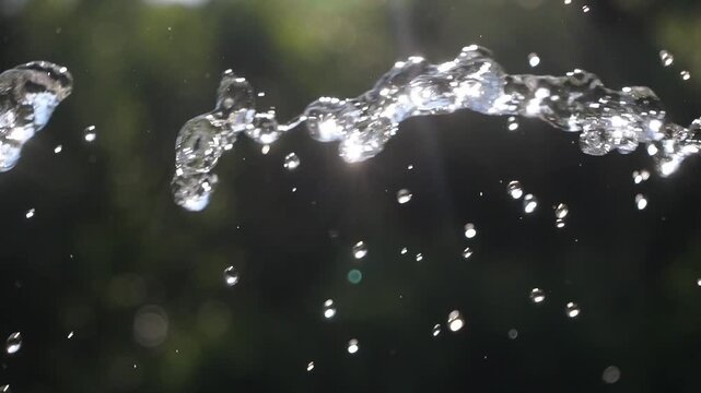 A jet of water flies in the air with splashes. Water drops in the summer.