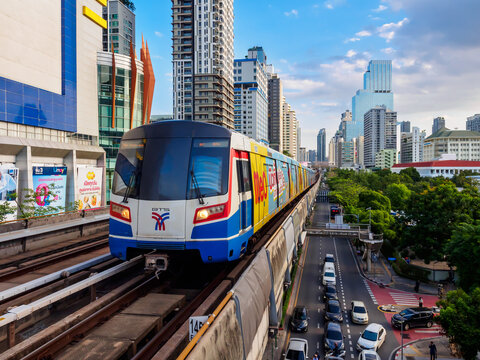 Bangkok, Thailand - July 8, 2026 : The BTS Skytrain runs in and out of Victory Monument Station in the afternoon, showing the other side of the station with stunning views of Bangkok office buildings.