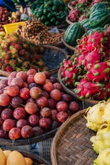 Variety of tropical fruits arranged at a market stall, featuring dragon fruit, watermelon, passion fruit and exotic produce. © olinchuk