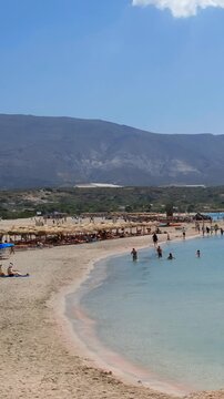 Vertical video of Elafonissi Beach with pink sand and turquoise shallow water. Crete. Greece