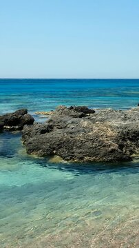 Vertical video of Elafonisi beach with pink sand and black rocks. Crete. Greece