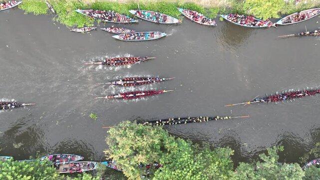 Gopalganj, Bangladesh - 30 October 2023: Aerial view of a traditional boat race with long narrow vessels and many rowers on the river.