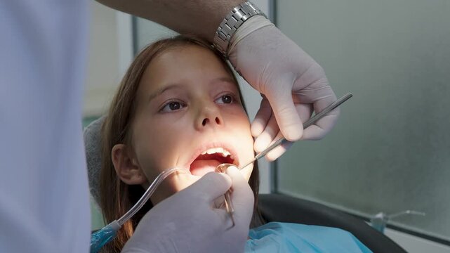 Pediatric dentist examining teeth with mirror and probe for young girl