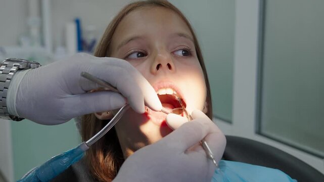 Pediatric dentist examining teeth with mirror and probe for young girl