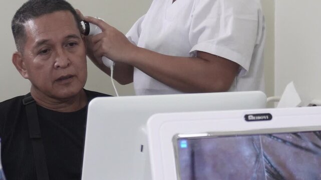 Digital scalp analyzer scanning a healthy middle aged man&rsquo;s scalp with live follicle imaging display for scalp diagnosis and hair care assessment.