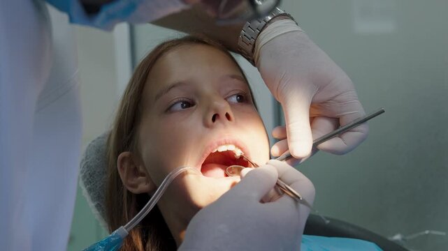 Pediatric dentist examining teeth with mirror and probe for young girl
