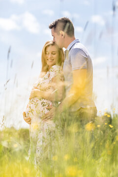 Young happy pregnant couple hugging in nature. Concept of love, relationship, care, marriage, family creation, pregnancy, parenting