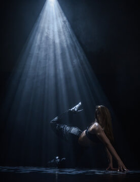 Mysterious silhouette of a female dancer under a blue spotlight beam. Concept of commercial template with copy space for musical show promo, theater poster and mental health therapy.